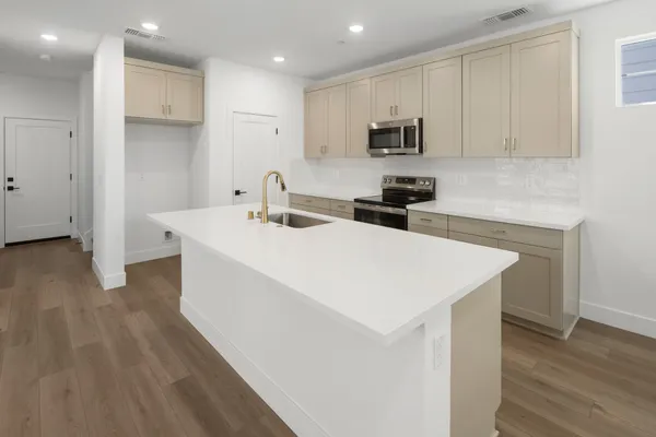Bright kitchen with large center island, light cabinetry and stainless steel appliances.