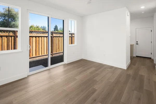 Bright dining area with sliding glass door, large windows and luxury vinyl plank flooring.