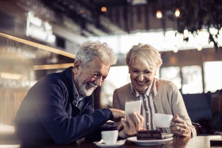 Two seniors sharing laughs and coffee in a restaurant