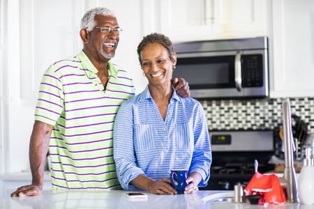 Senior couple enjoying laughs and coffee in the kitchen