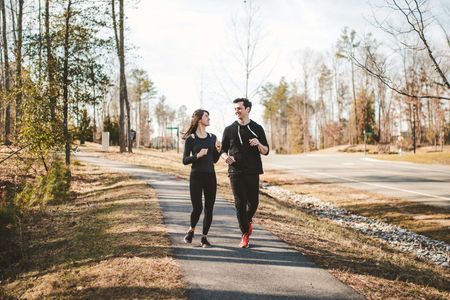 Man and woman happily jogging along a sidewalk