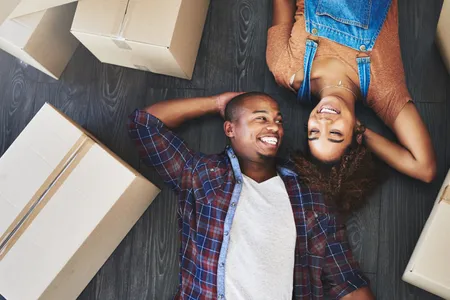 Overhead view of couple happily lying beside their moving boxes