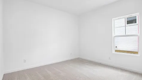 Bedroom of the Chestnut by Arbor Homes with a large window and ecru carpet