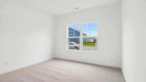 Bedroom of the Chestnut by Arbor Homes with a large window and ecru carpet