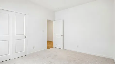 Bedroom of the Chestnut by Arbor Homes with a large window and ecru carpet